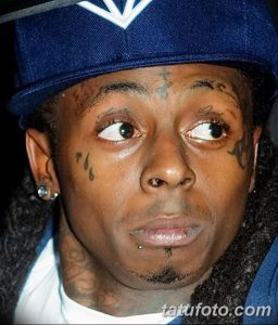 Фото тату на лице рэпера Lil Wayne. Изображены черные татуировки в виде капель слез под глазами и надписи на бровях.