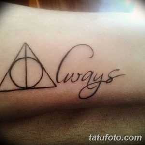 Черно-белое фото татуировки на руке с надписью "Always" каллиграфическим шрифтом и небольшим треугольником, символизирующим Дары Смерти.