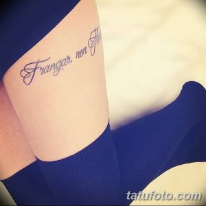 Фото тату на бедре с надписью на латыни 'Frangar, non flectar'. Изящный шрифт, классический стиль, сильный символ.