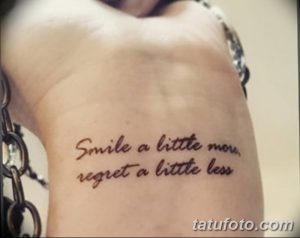 Фото тату на груди с надписью 'Smile a little more, regret a little less'. Рукописный шрифт, позитивный смысл, вдохновляющий рисунок.