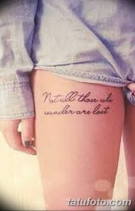 Фото тату надписи 'Not all those who wander are lost' на бедре. Черные чернила, каллиграфический шрифт. Идея для тату для путешественников.