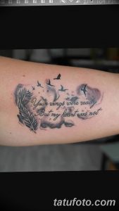 Фото тату: черное перо, летящие птицы и надпись "Your wings were ready But my heart was not" на руке.