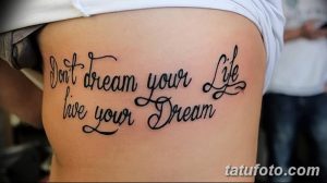 Фото тату: фраза "Don't dream your life live your dream" на боку, выполненная красивым шрифтом.