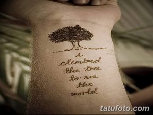 Фото тату с изображением дерева и надписью 'i climbed the tree to see the world' на запястье. Черный цвет, минимализм, вдохновляющая фраза.