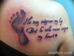 Фото тату с отпечатком детской ножки и надписью 'He may outgrow my lap But he will never outgrow my heart', выполненной на плече. Черно-белая татуировка, символизирующая безусловную материнскую любовь.