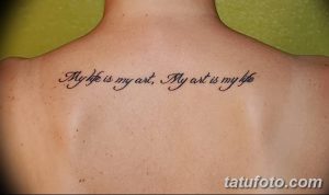 Фото тату с надписью 'My life is my art, My art is my life', выполненной каллиграфическим шрифтом на спине. Черно-белая татуировка, символизирующая единение жизни и творчества.