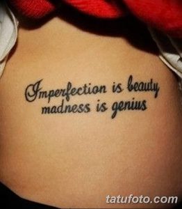 Фото тату с надписью 'Imperfection is beauty, madness is genius', выполненной каллиграфическим шрифтом на боку. Черно-белая татуировка, символизирующая принятие своей уникальности.