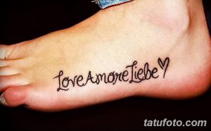Фото тату на стопе с надписью 'Love Amore Liebe' и изображением сердца. Черный цвет, минималистичный стиль, романтичный смысл.