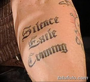 Фото тату на предплечье с готической надписью 'Silence Exile Coming'. Черный цвет, декоративный шрифт, мрачный стиль.