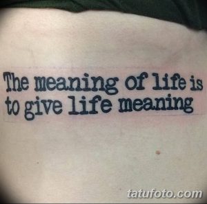 Фото тату с надписью 'The meaning of life is to give life meaning' на спине. Черный контур, минималистичный стиль, вдохновляющая цитата.