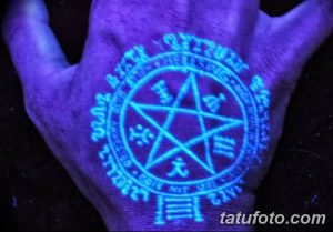 Фото тату: UV-татуировка на ладони в виде мистического символа с пентаграммой и надписями. Загадочный и привлекательный рисунок татуировки, светящийся в ультрафиолете.