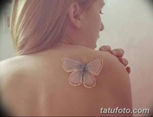 Фото тату: изящная белая татуировка в виде бабочки на лопатке. Детализированный рисунок татуировки с проработанными крыльями.