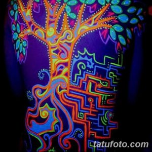 Фото тату: красочная UV-татуировка на спине, изображающая дерево жизни с яркими листьями и сложный лабиринт. Необычный рисунок татуировки, светящийся в ультрафиолете.