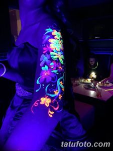 Фото тату: красочный букет цветов, выполненный в технике UV татуировки на руке. Яркие неоновые оттенки под ультрафиолетовым светом.