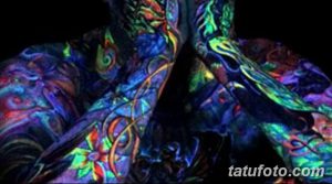 Фото тату: масштабная татуировка, покрывающая спину и бока, светящаяся в ультрафиолете. Абстрактные узоры и яркие цвета.