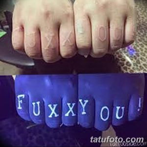 Фотография татуировки с надписью "FUCKYOU!" на пальцах, светящейся в ультрафиолете. Яркий и вызывающий рисунок.