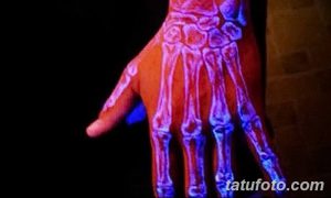 Фото флуоресцентного тату на руке, изображающего скелет костей. Рисунок светится в ультрафиолете, создавая жутковатый и завораживающий эффект.