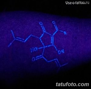 Фото ультрафиолетовой татуировки с изображением молекулярной формулы, светящейся в темноте под воздействием ультрафиолетового света. Татуировка выполнена на руке.