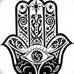 Черно-белое фото тату, изображающее Хамасу с открытым глазом в центре, украшенную сложным орнаментом и символами.