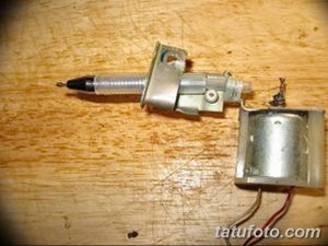 Фотография самодельной тату-машинки с акцентом на моторчик и иглу. Видны детали крепления и механизм работы.