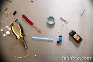 Фотография набора инструментов, используемых для создания самодельной тату-машинки: ножницы, ручки, провода, изолента и другие предметы.