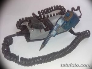 Тату машинка с подключенным блоком питания и витой спиралью провода. Голубой корпус машинки и черная обмотка.