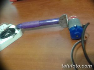 Упрощенная самодельная тату-машинка с фиолетовым корпусом и синим блоком питания. Демонстрирует базовый принцип работы.