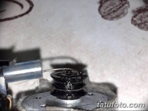 Фотография крупным планом бойкера и контактного винта тату-машинки. Видны детали и их соединение.