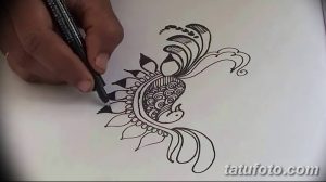 Фото процесса создания эскиза тату мехенди, демонстрирующее руку художника, рисующего хной на бумаге. Идеально для тех, кто интересуется искусством мехенди.