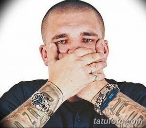 Фотография Басты с татуировками на предплечьях, закрывающего лицо руками. Видны часы и браслеты на запястьях.