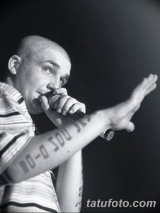 Мужчина с татуировками на руке, выступающий с микрофоном. Фотография передает атмосферу страсти и энергии.