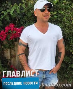 Фотография Дмитрия Нагиева в белой футболке и джинсах с татуировкой на руке. Видна татуировка в виде надписи.