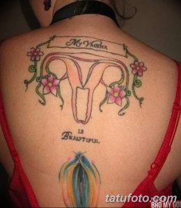 Фото тату матки с розовыми цветами и надписью 'My Vagina is Beautiful' на спине девушки. Детализированный рисунок татуировки.