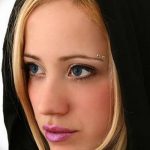 Фото пирсинга брови девушки. Серебряные шипы, длинные волосы и выразительный взгляд.