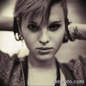 Фото пирсинга брови, губы и ушей девушки. Серебряные украшения, черно-белое фото, выразительный взгляд.