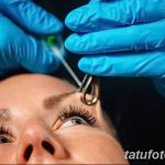 Фотография процесса пирсинга брови, где мастер в голубых перчатках выполняет процедуру. Детальный снимок для тех, кто интересуется процессом пирсинга.