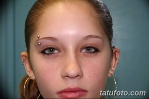 Фотография девушки с пирсингом брови и ушей, с длинными волосами и легким макияжем. Идеальный пример для вдохновения перед пирсингом.