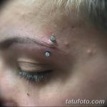 Фото тату: два серебристых прокола над бровью. Минималистичный пирсинг лица, акцент на глаза и брови.