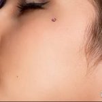 Фото пирсинга щеки с серебряным кольцом. Крупный план, вид сбоку, акцент на форме лица и украшении. Идеи для пирсинга лица.