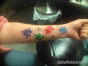 Несколько разноцветных татуировок с изображением элементов пазла на запястье. Яркие цвета: синий, красный, зеленый, желтый.
