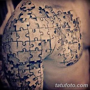 Фото тату: татуировка в стиле blackwork, изображающая фрагменты пазла на плече, выполненная только черными линиями.