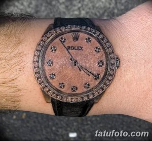 Татуировка на запястье с изображением часов Rolex, украшенных бриллиантами. Реалистичный рисунок татуировки, выполненный в серых и черных тонах.