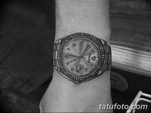 Черно-белое фото татуировки с реалистичным изображением часов Rolex на мужском запястье. Детализированный рисунок передает текстуру металла и циферблата.