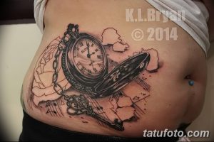Фото тату карманных часов на боку с открывающейся крышкой, ключом и летящими страницами, выполненное в черно-серых тонах.