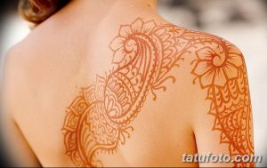 Фото тату мехенди на спине: коричневый цветочный узор с завитками, расположенный вдоль позвоночника.