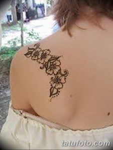 Фото тату мехенди на спине девушки, с детализированным цветочным узором в коричневых тонах. Изящный и женственный дизайн.