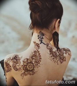 Фото татуировки хной на спине и шее девушки. Рисунок выполнен в традиционном восточном стиле с использованием сложных узоров и растительных мотивов.