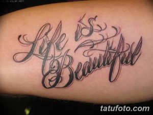 Фото тату: каллиграфическая надпись 'Life is Beautiful' на руке, выполненная в черном цвете. Элегантный и вдохновляющий дизайн.