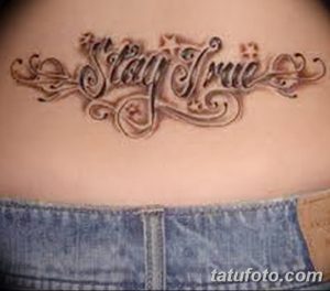 Фото тату: татуировка с надписью "Stay True" на талии. Элегантный шрифт и декоративные элементы.