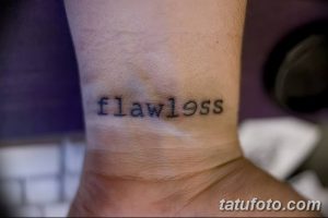 Фото тату с надписью 'flawless' на запястье. Минималистичная татуировка черными чернилами, выполненная простым шрифтом.